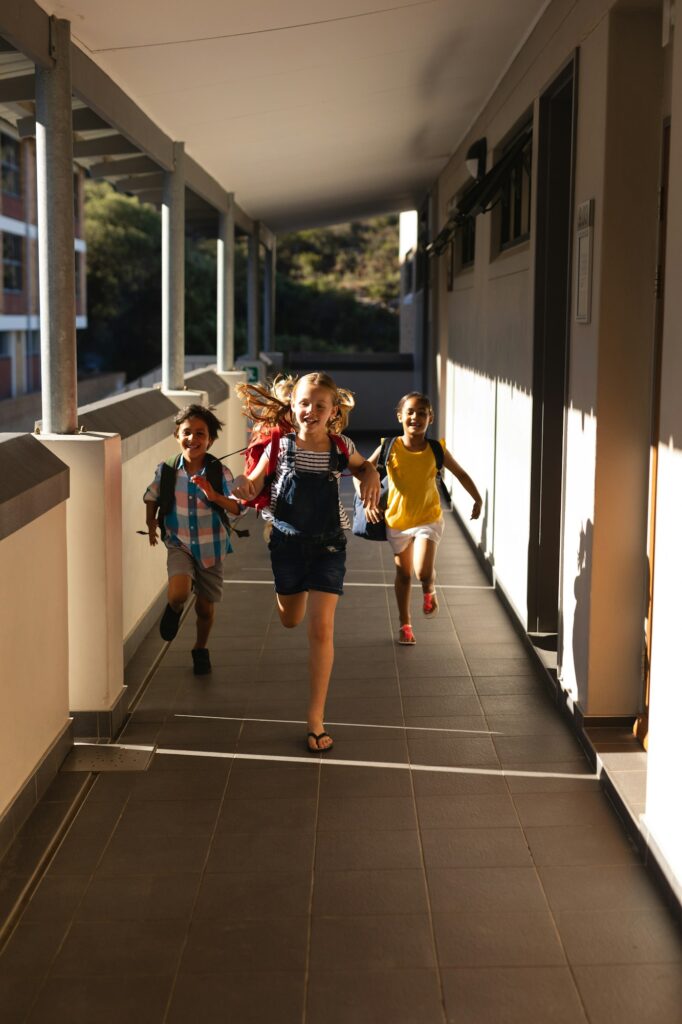 Front view of schoolkids with schoolbags running in hallway of elementary school